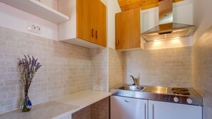 A compact kitchen with white cabinets, a stainless steel sink, and a built-in oven. - Apartments Stipe (Mali Losinj)