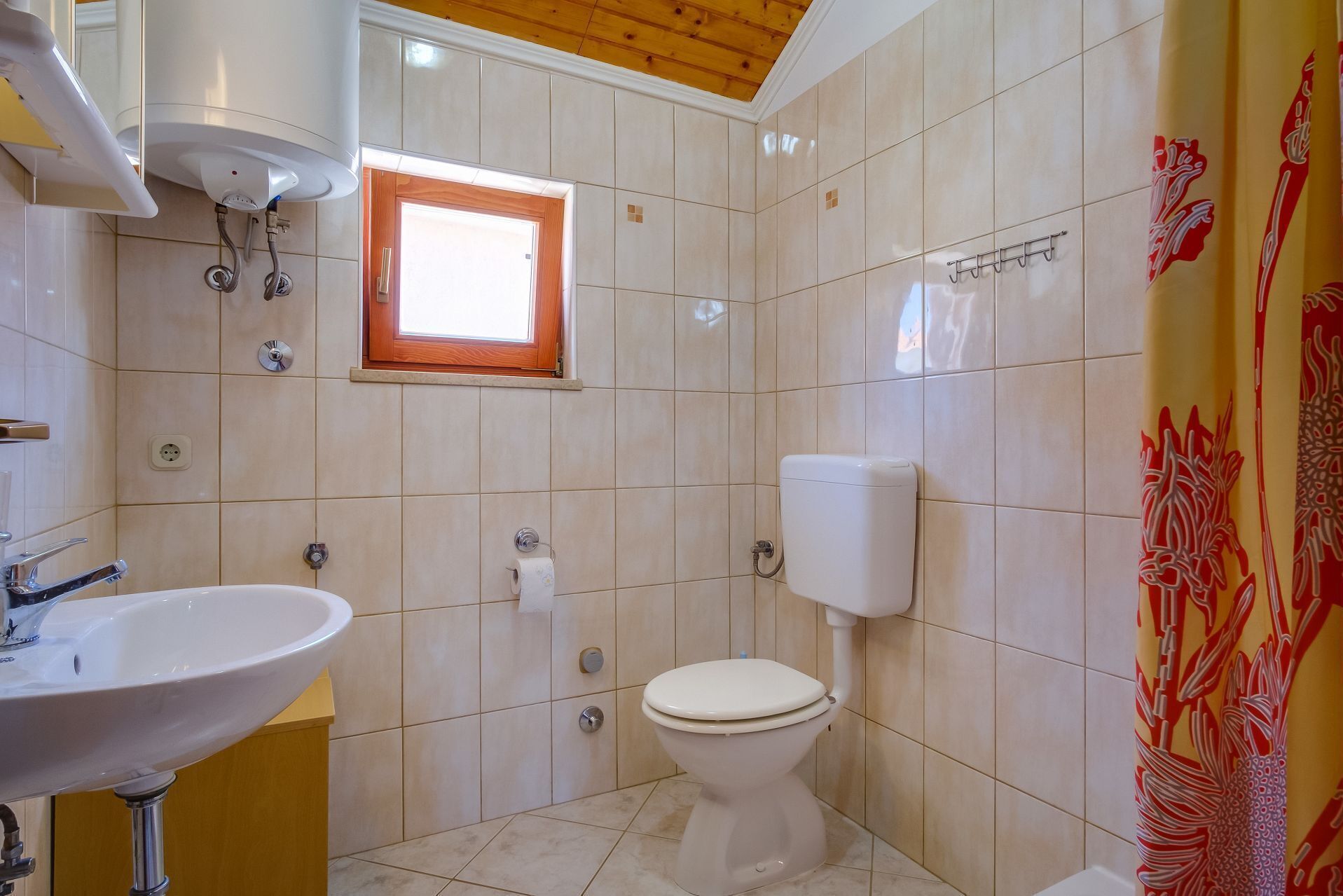 A bathroom with a sink, toilet, and window.
