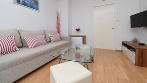 Ein modernes Wohnzimmer mit einer Couch, einem Glastisch und einem Fernseher auf einem Holzboden.