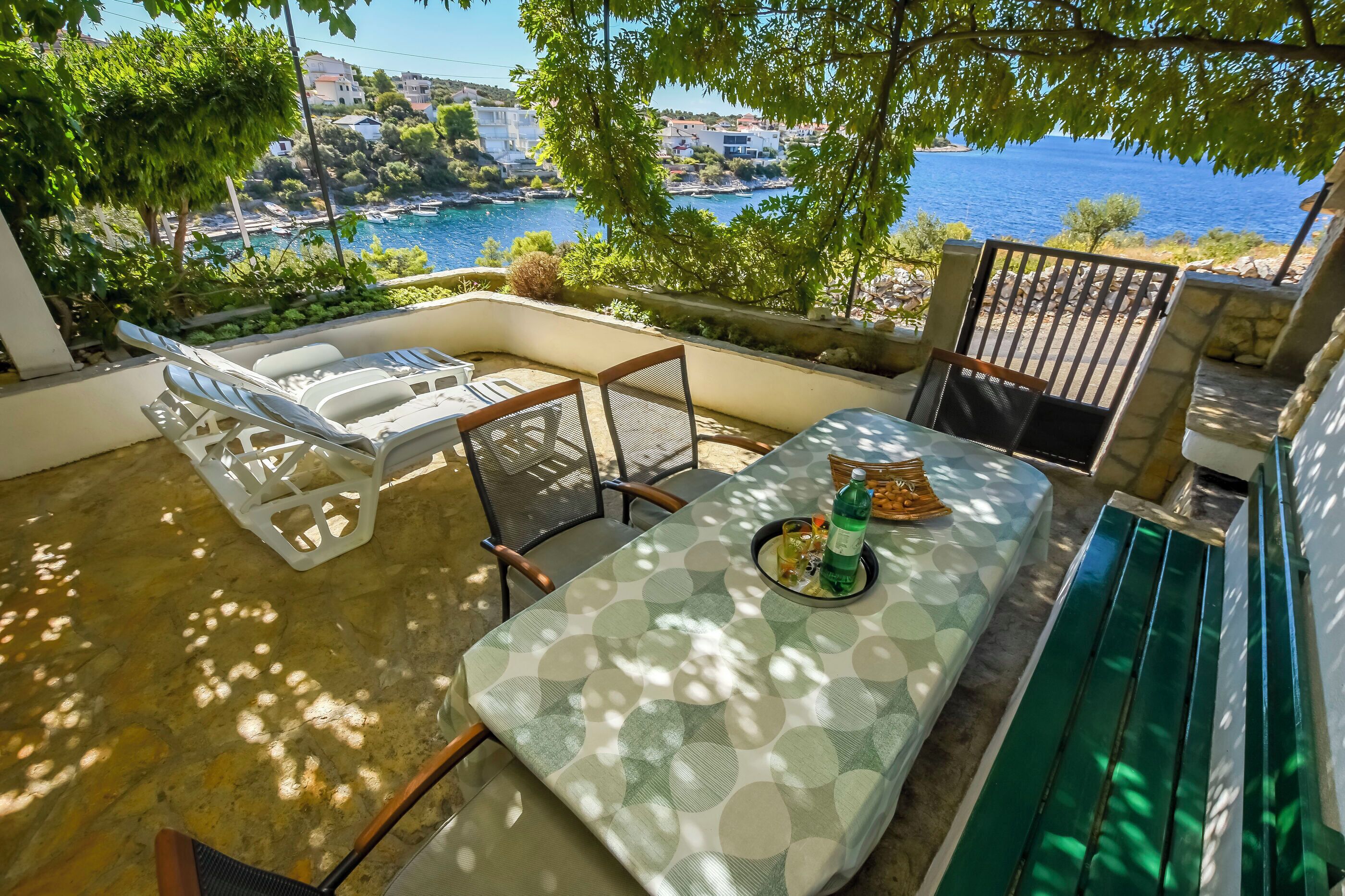 A terrace with a table, chairs, and a view of the sea.