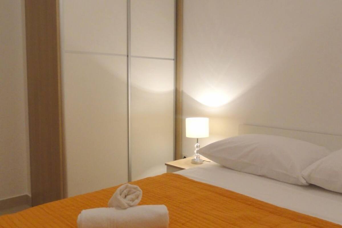 A hotel room with a bed, a nightstand, a lamp, and a wardrobe.