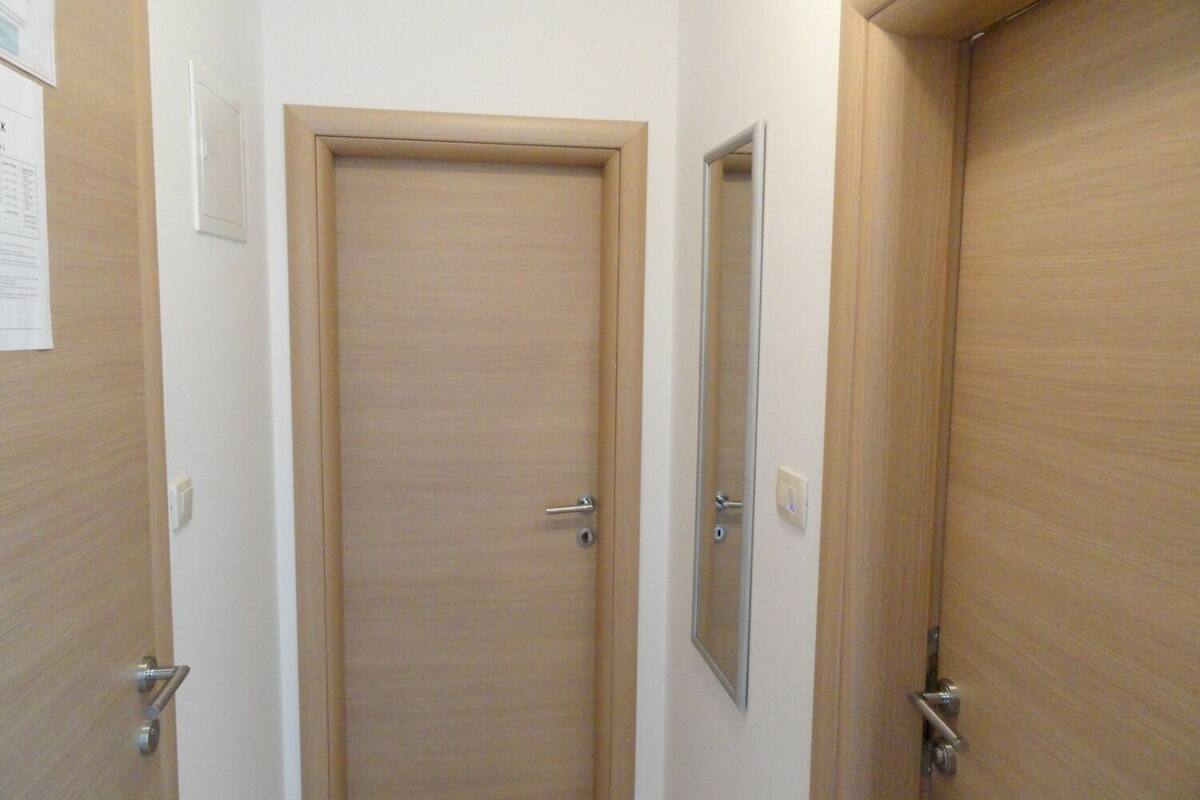 A hallway with wooden doors, one of which has a mirror on the wall.