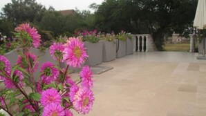 Ein Innenhof mit Fliesenboden und einer Reihe von Pflanzgefässen mit rosa Blüten.
