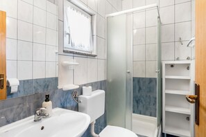 Ein Badezimmer mit weißem Waschbecken, Toilette und einer Duschkabine.