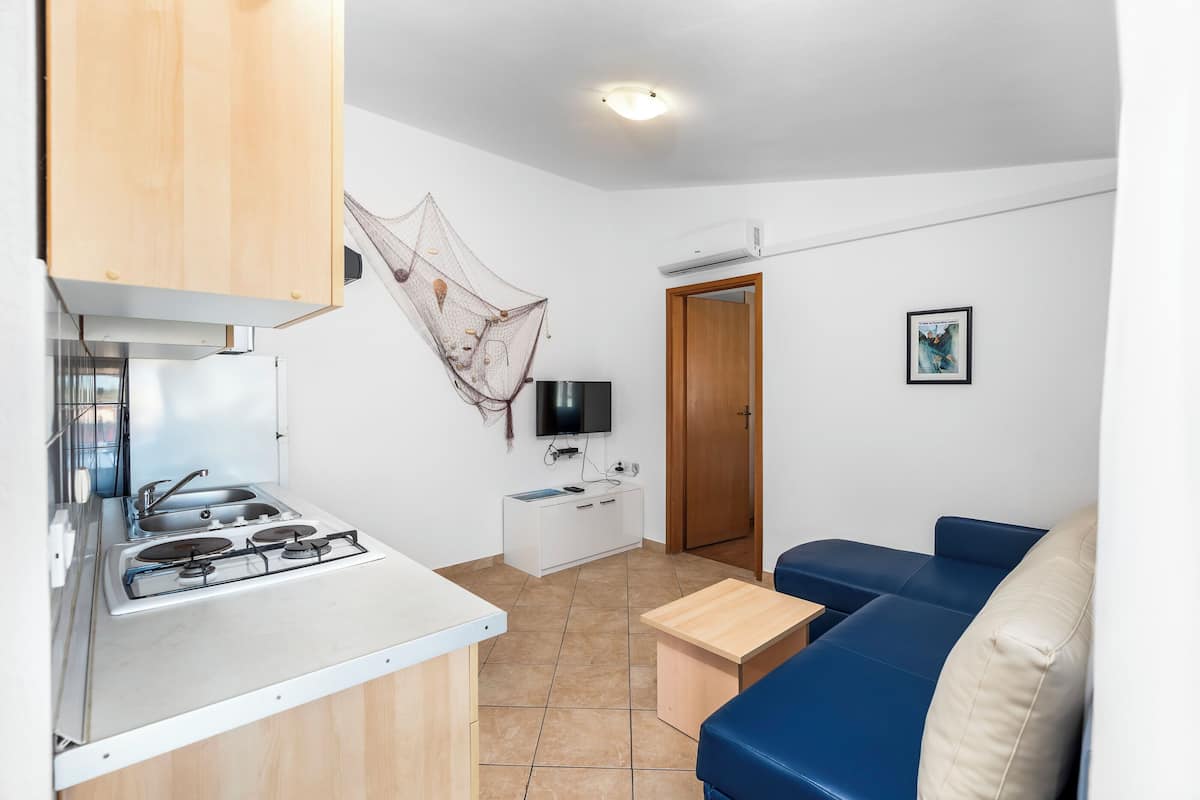 Eine kleine Küche mit Gaskochfeld, einem weißen Schrank und einer Holzzieldecke.