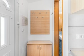 Ein Flur mit einem Holzschrank, einem an der Wand befestigten Kleiderhaken und einer Tür zu einem Badezimmer.