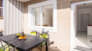 Un comedor con una mesa dispuesta para dos, una ventana con vistas y una puerta que da a una cocina.