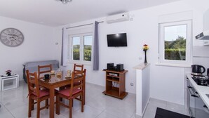 Una cocina moderna con estufa, televisor de pantalla plana y comedor con mesa y sillas.