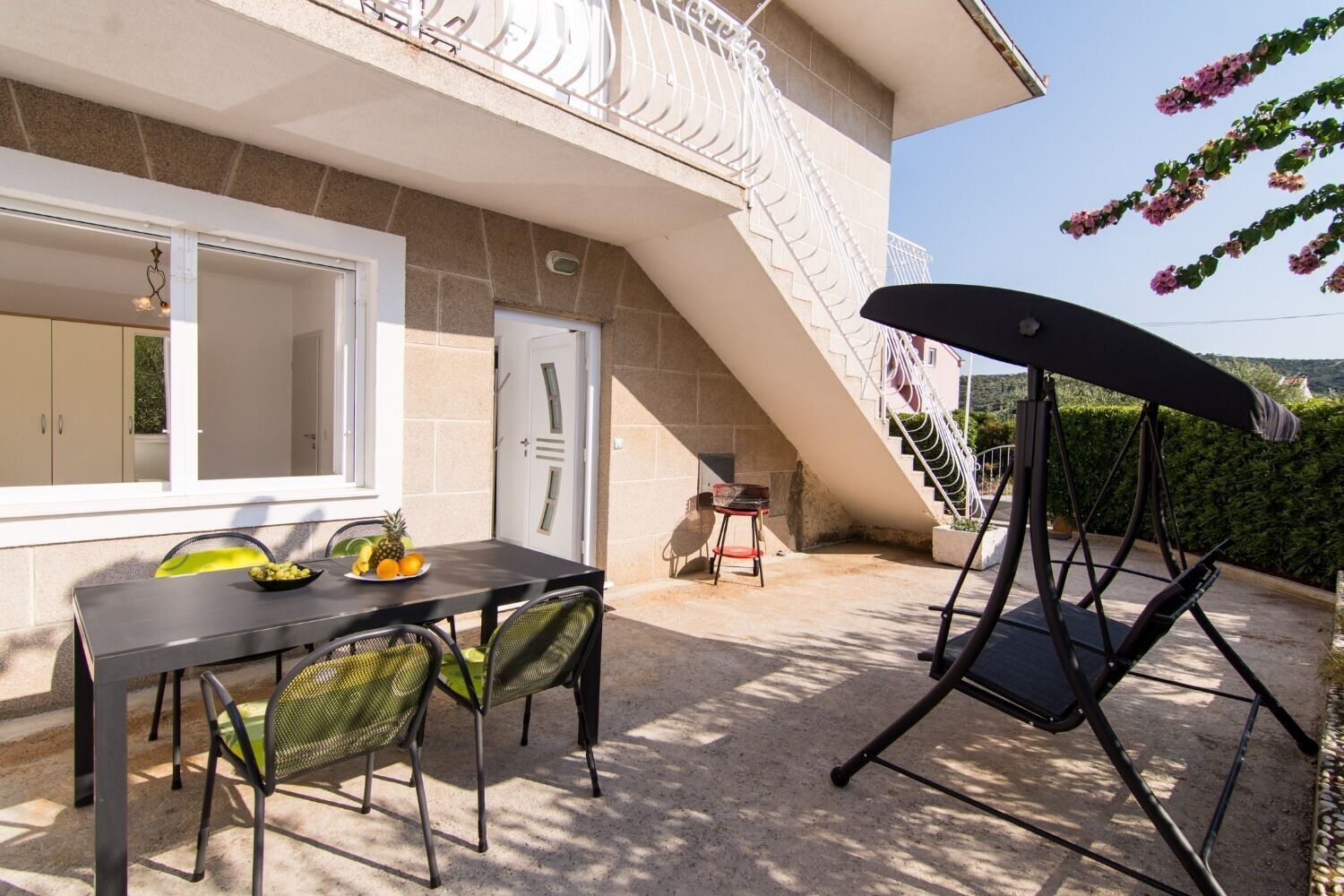 Ein Balkon mit Esstisch, Schaukelstuhl und Treppe zu einer oberen Etage.