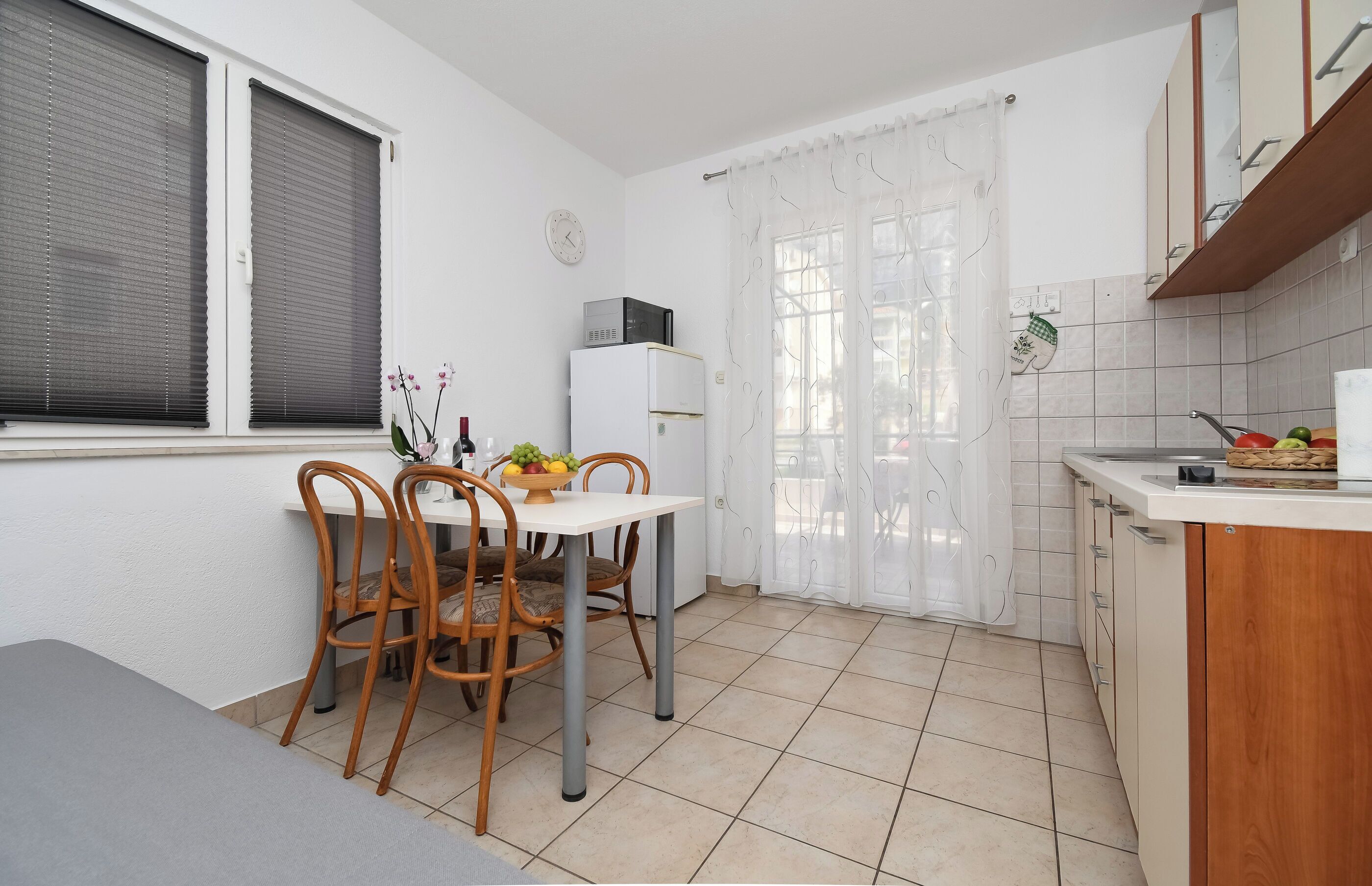 Een kleine keuken met een eettafel, stoelen, een koelkast en een gootsteen.