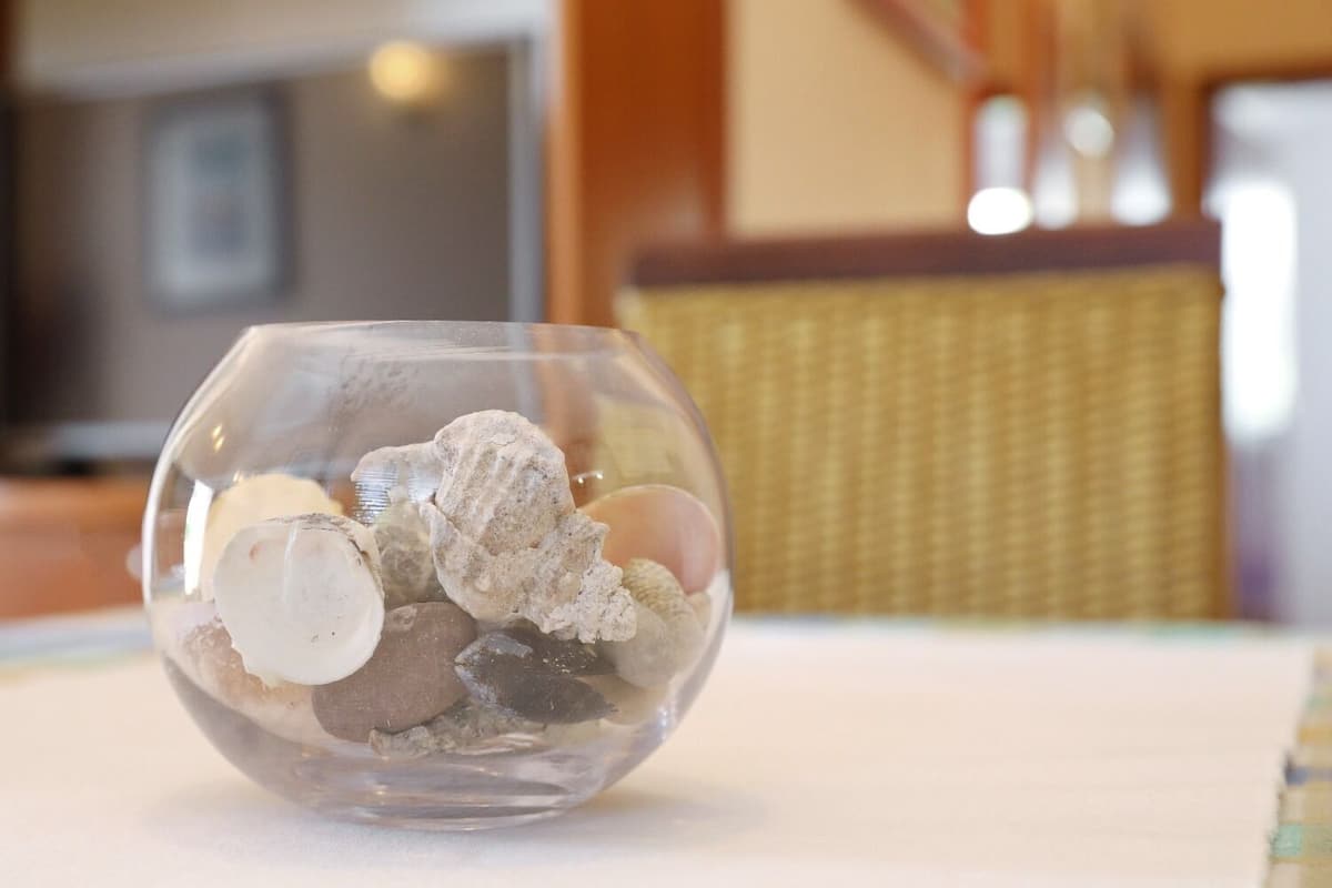 A clear glass bowl containing various stones on a table.