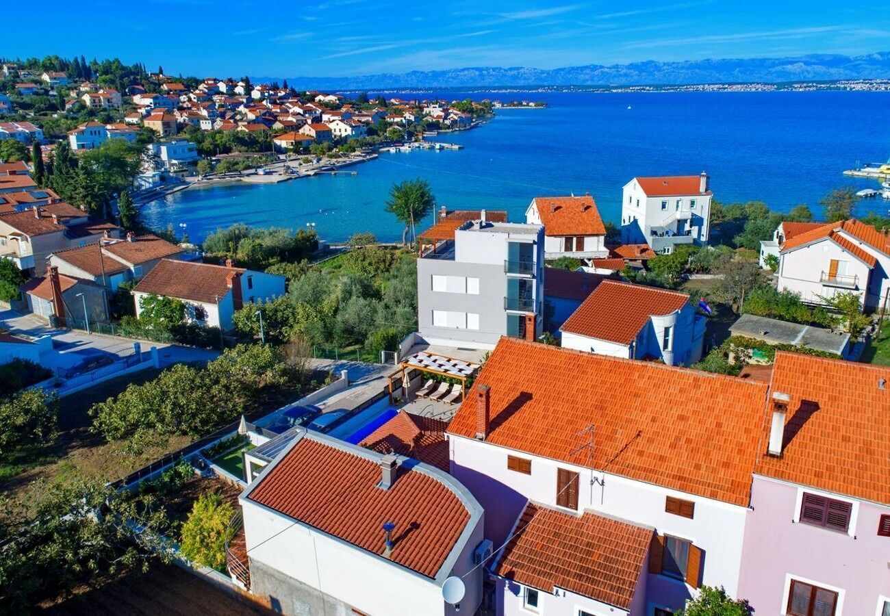 A coastal residential area with houses featuring red-tiled roofs and a view of the sea.