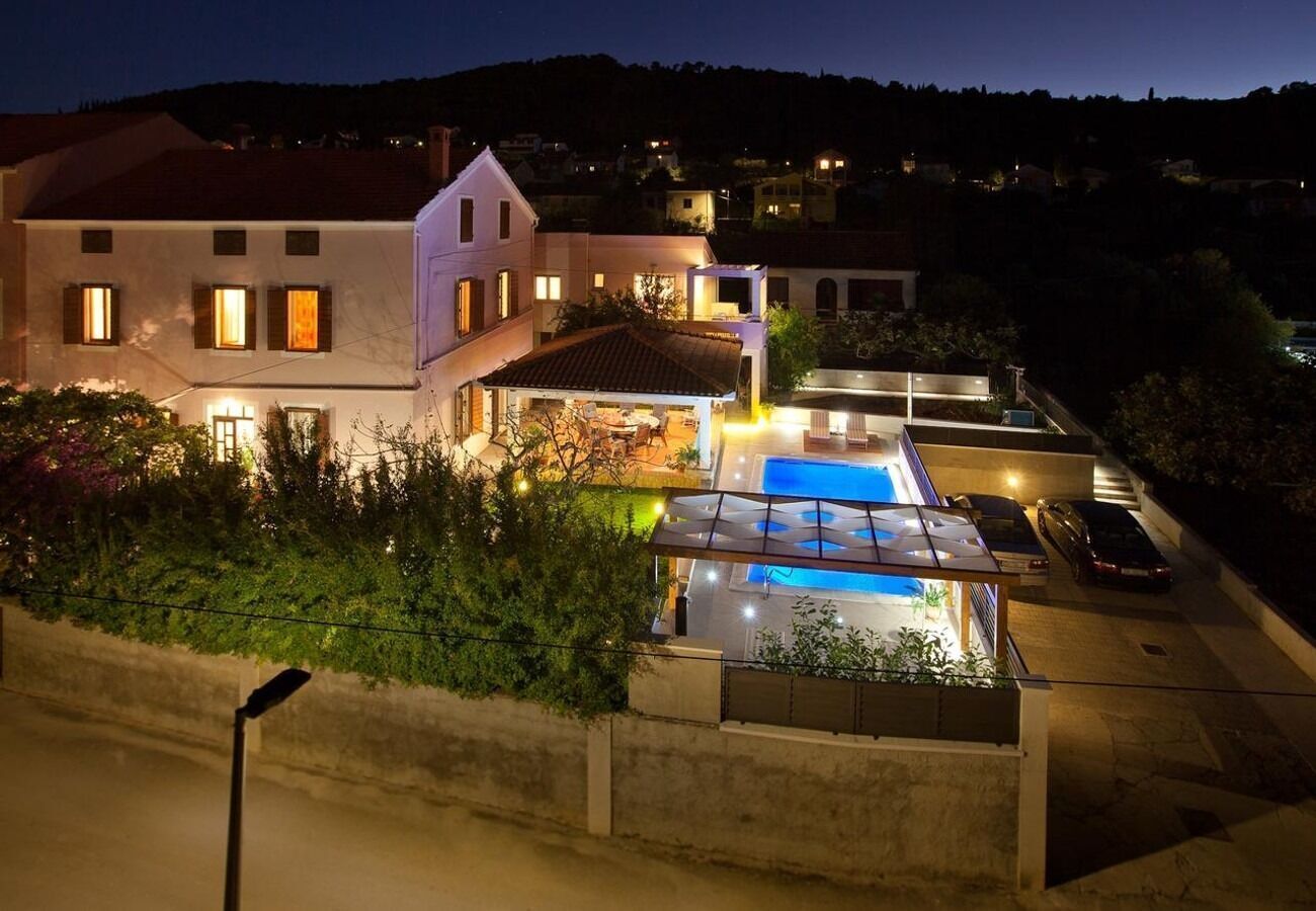 A modern house with a swimming pool, a covered patio, and a car parked in the driveway.