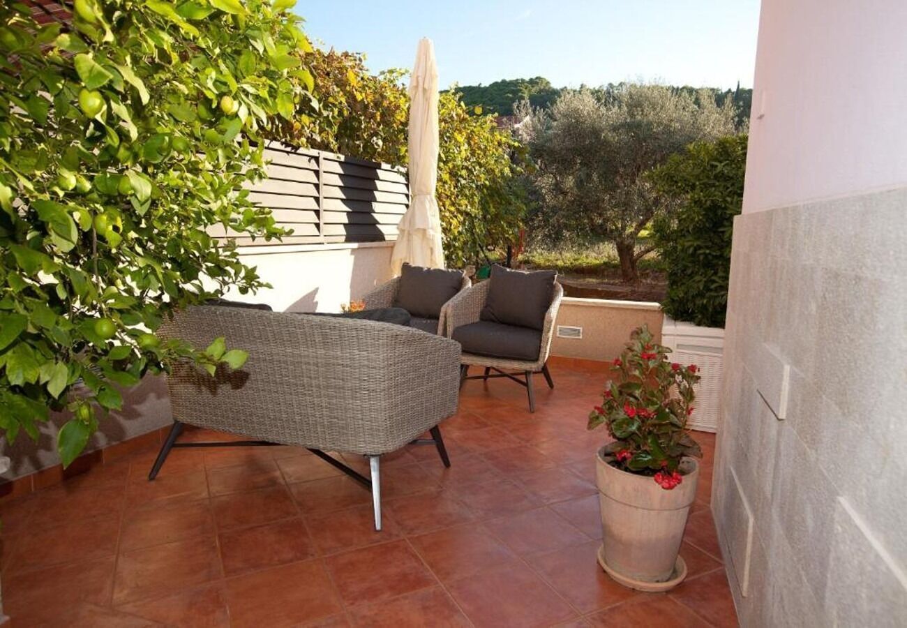 An outdoor patio with wicker furniture, a potted plant, and a view of the surrounding landscape.