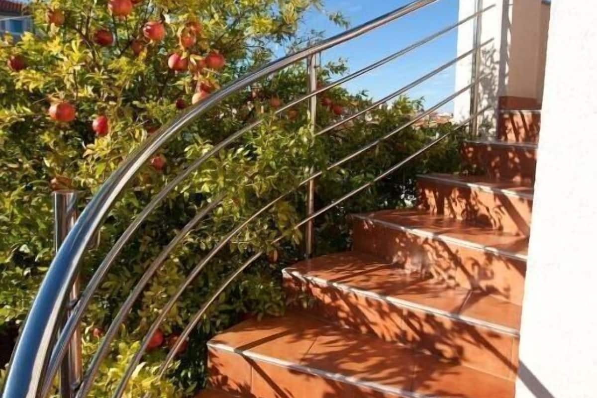 Un escalier en colimaçon, dont les marches sont recouvertes de carreaux rouges, mène à un mur blanc.
