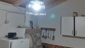 A kitchen with a hanging light fixture, a refrigerator, and a sink with a floral backsplash. - House Senka1 (Vela Luka)