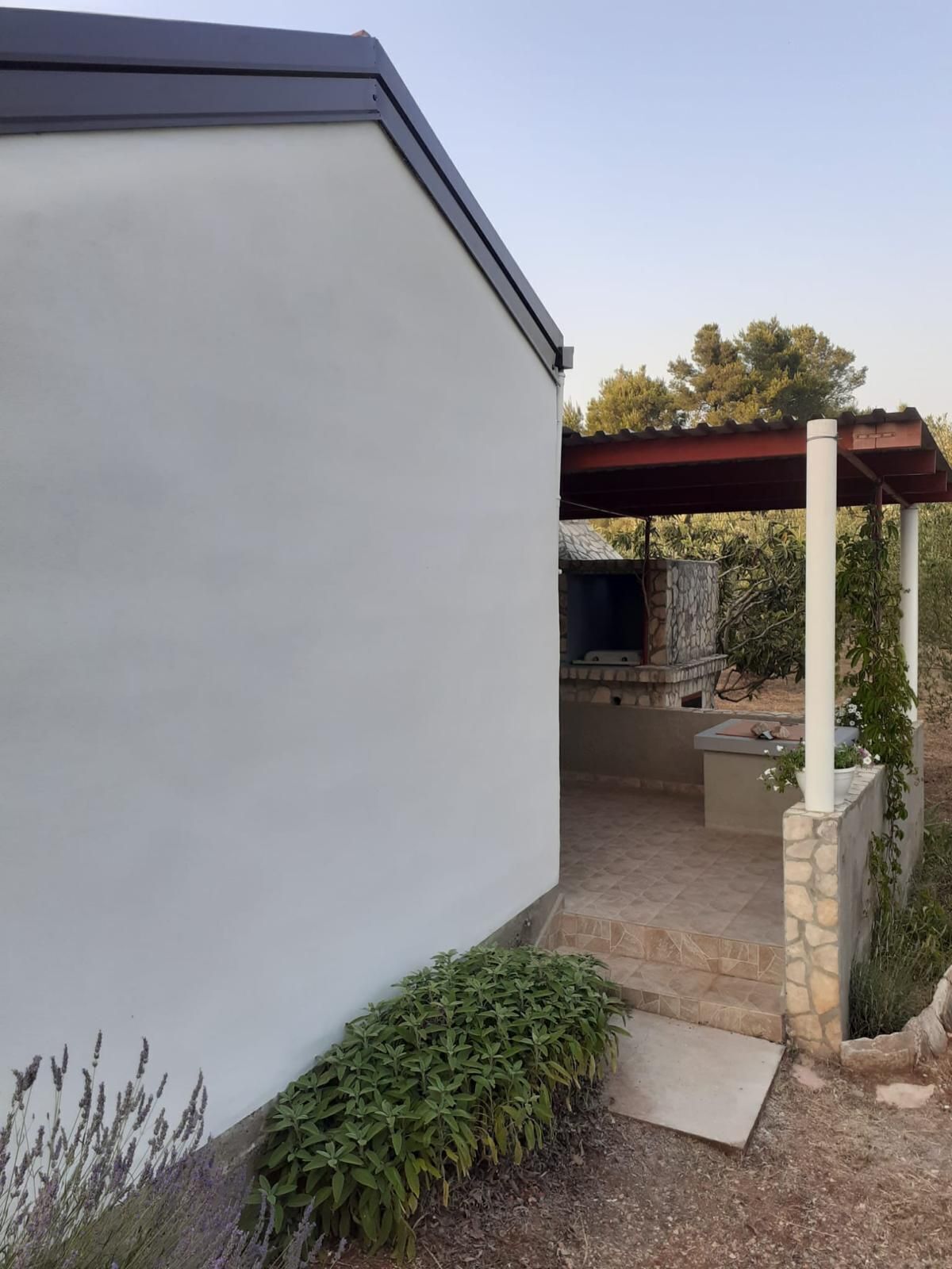 Una casa moderna con un patio, un muro de piedra y un espacio exterior cubierto con una parrilla.