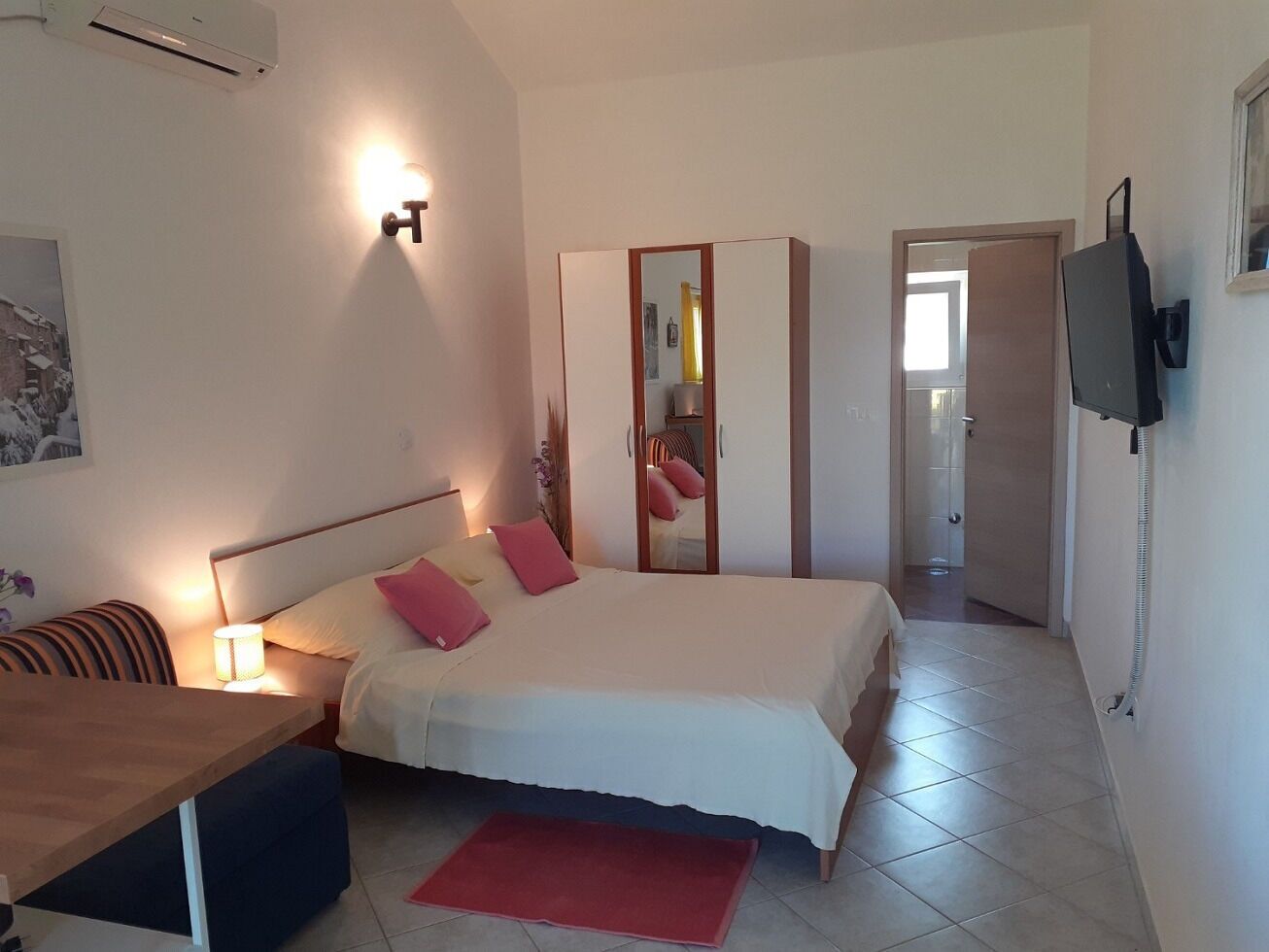 A hotel room with a bed, bedside table, lamp, and a mirror.