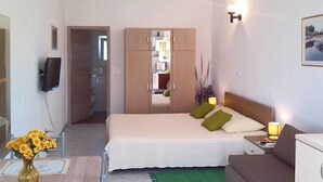 A bedroom with a bed, bedside table, lamp, and a small desk with a vase of flowers. - Apartment Brane (Preko)