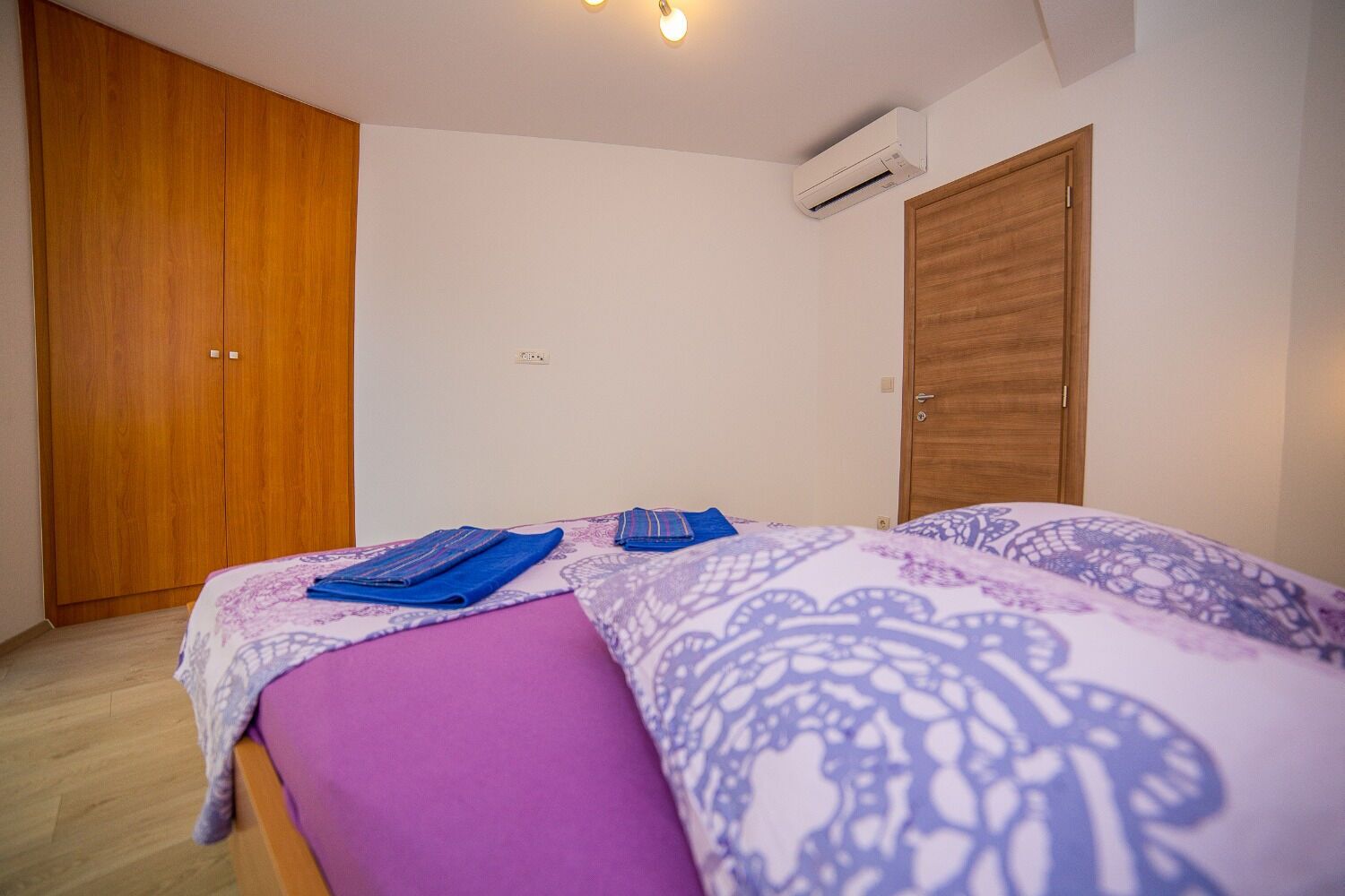 Un dormitorio con cama, armario de madera y aire acondicionado.