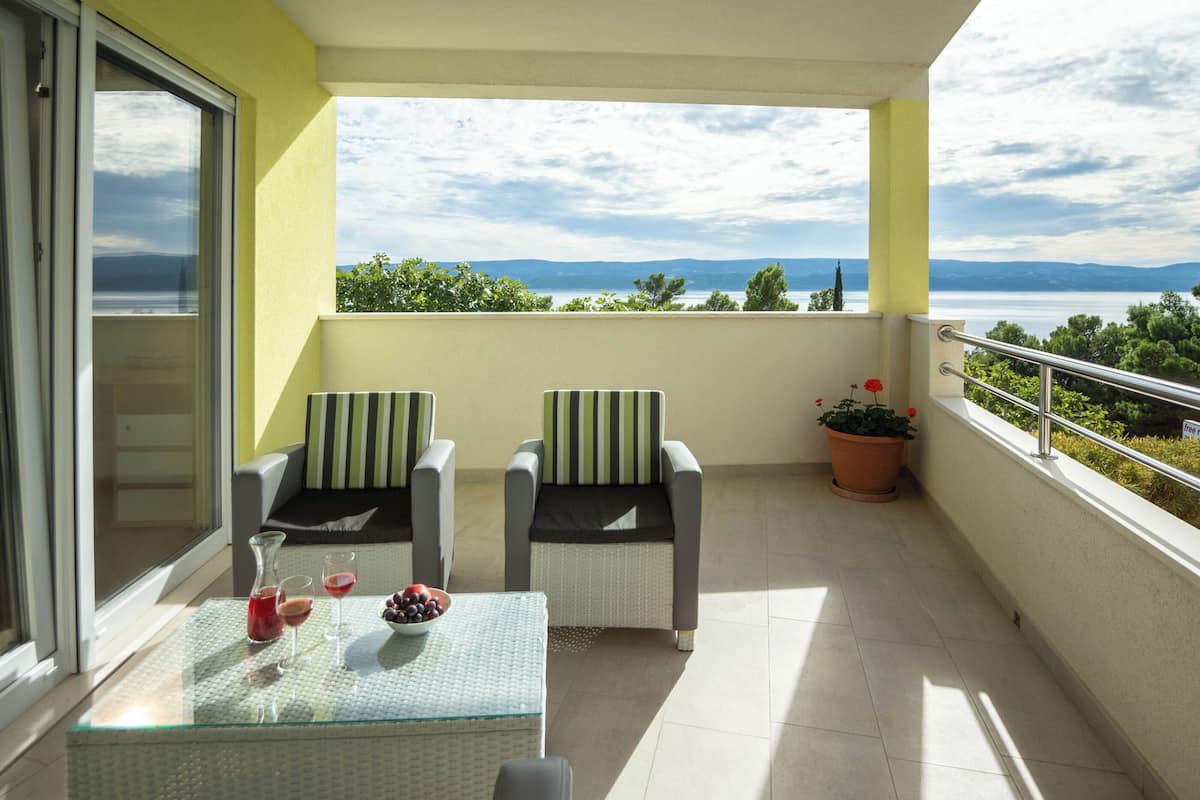 A balcony with two chairs, a table, and a potted plant.
