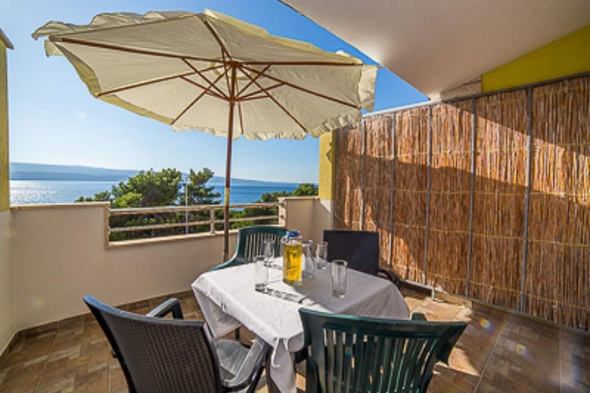A balcony with a table, chairs, and an umbrella.
