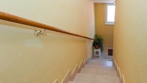 Eine Treppe mit hölzernem Geländer, hellbeige Wänden und einer Topfpflanze am oberen Ende.