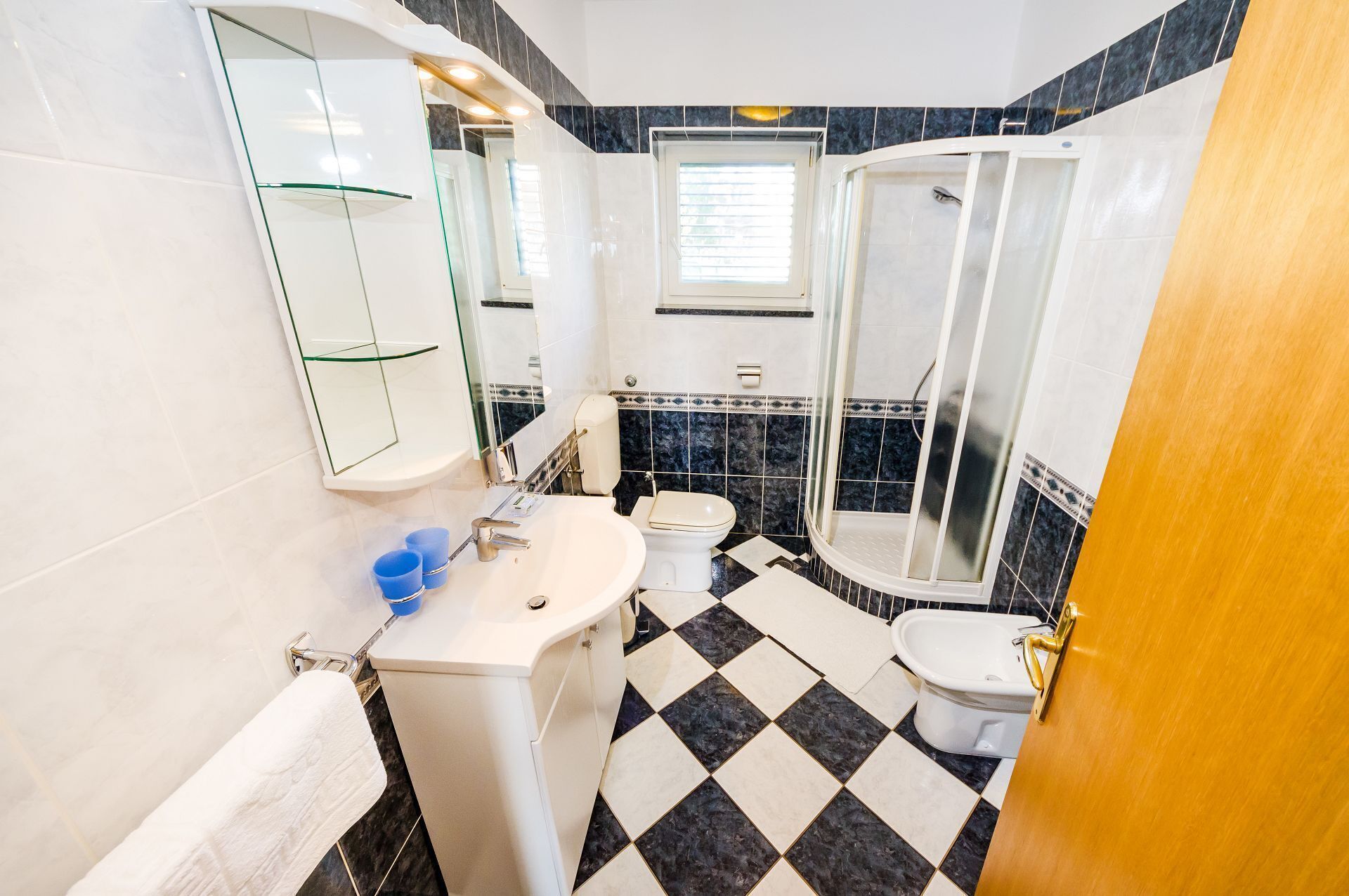 Un bany amb un lavabo blanc, un vàter, una cabina de dutxa de vidre i un mirall.