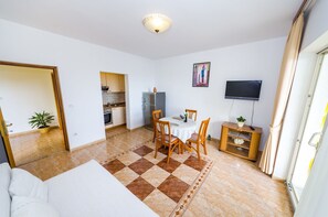 A compact living space with a dining area, kitchenette, and a TV mounted on the wall. - Apartments Cloe (Zadar)