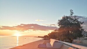 Une promenade en bois menant à une plage, avec un coucher de soleil en arrière-plan.