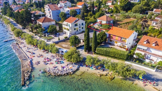Vue aérienne d’une ville côtière avec une plage, des maisons et une côte rocheuse.