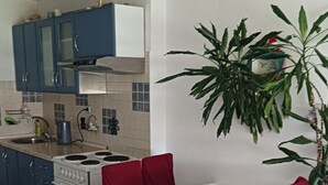 A dining area with a table and chairs, a kitchen in the background, and a potted plant. - Apartment Dragica 1 (Split)