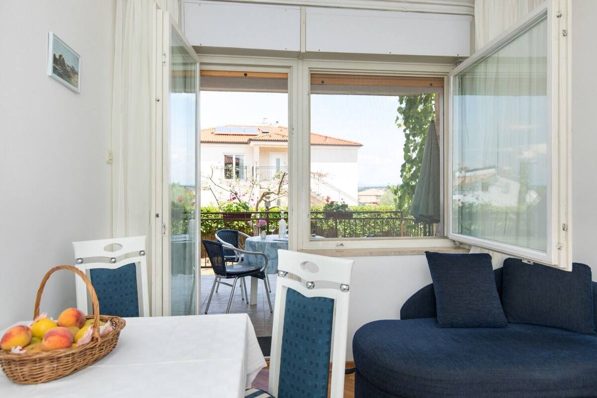 Ein Zimmer mit Balkon, einem Tisch mit Stühlen und einer Couch.