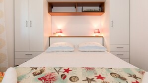 Een slaapkamer met een bed, twee bedlampen en een plank boven het bed.