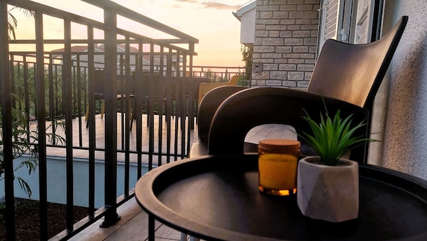 A balcony with a chair, a small table, a candle, and a potted plant. - Apartment Korni (Biograd na Moru)