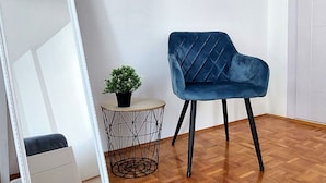 A room with a blue velvet chair, a small round table with a plant, and a geometric wireframe side table. - Apartment Korni (Biograd na Moru)