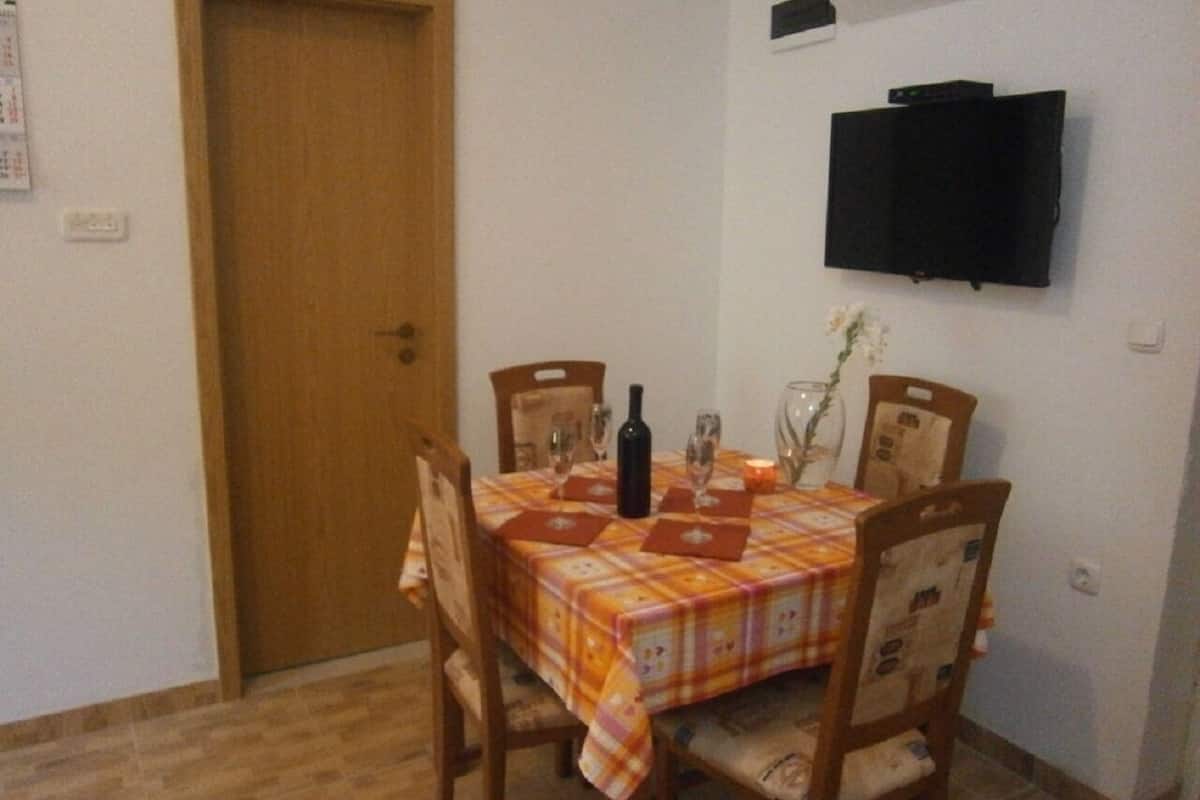 A dining area with a table set for four, chairs, a bottle, glasses, and a candle.
