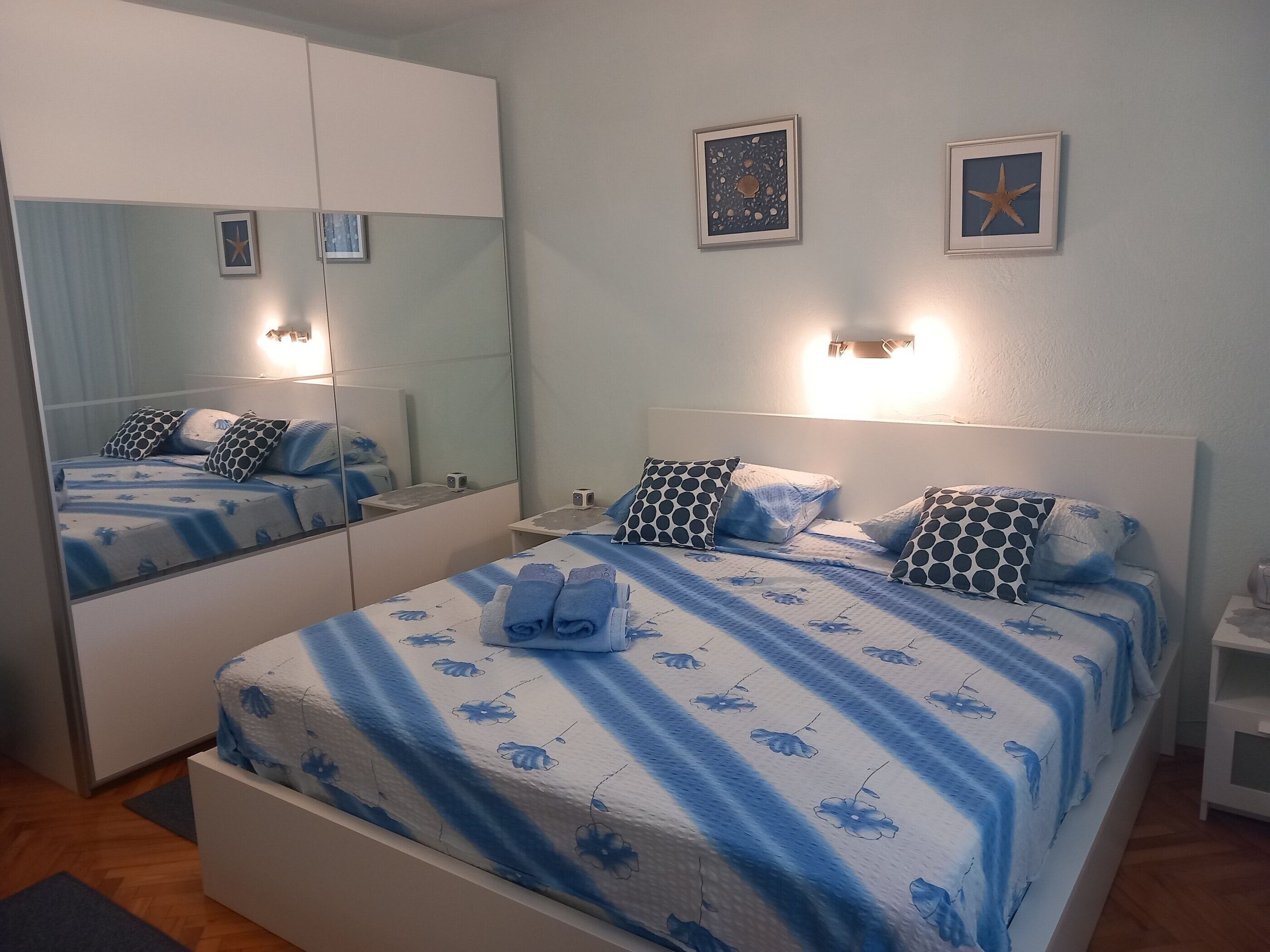 A bedroom with a bed, a nightstand, a mirror, and wall art.