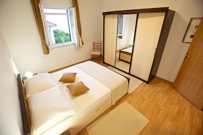 A bedroom with a bed, a chair, a wardrobe, and a window. - Apartments Paula (Sutivan)