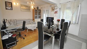 A dining area with a table, chairs, a TV, and a bookshelf. - Apartments Ivica (Kastela)