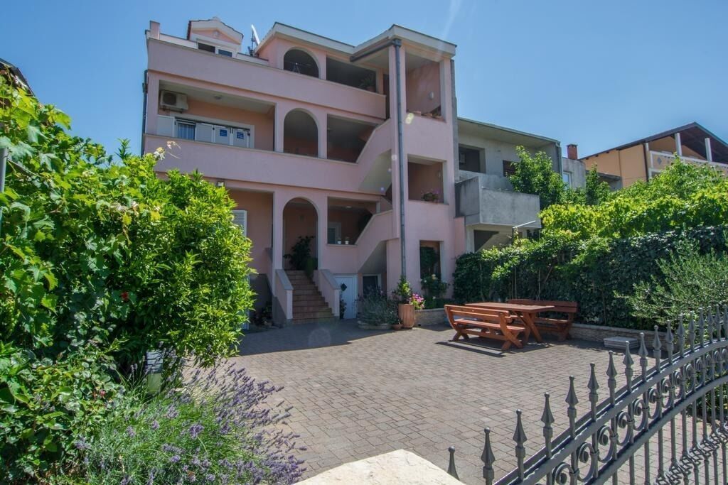 A multi-story building with a central staircase, outdoor seating, and lush greenery.