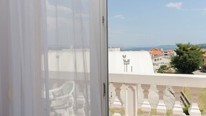 Ein Balkon mit Blick auf eine Küstenstadt, darunter Häuser und ein klarer Himmel.