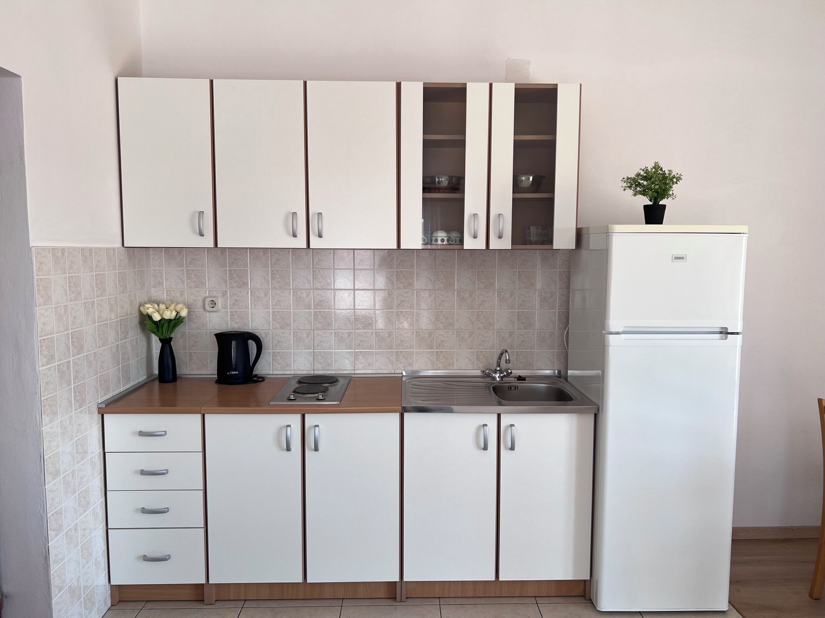 A kitchen with white cabinets, a sink, a stove, and a refrigerator.