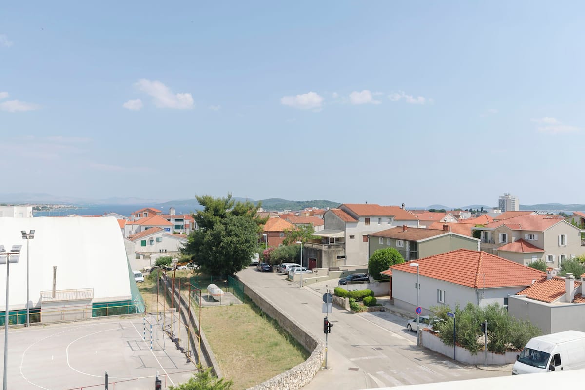 A residential area with houses, a basketball court, and a road.