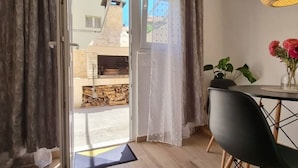 A room with a sliding glass door leading outside, a dining table with chairs, a hanging light fixture, and a potted plant. - Apartments Edvard (Split)