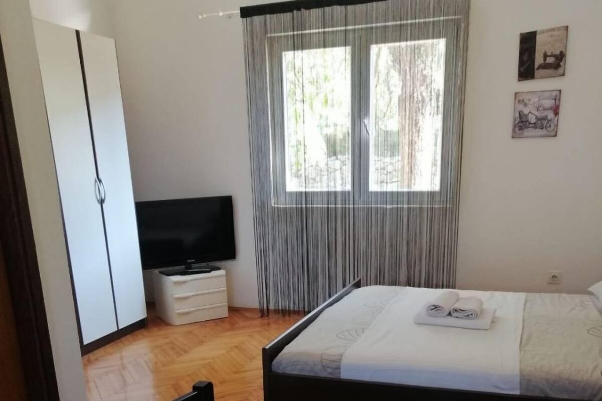 A hotel room with two beds, a wardrobe, a television, and a window with curtains.