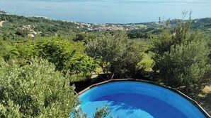 A swimming pool surrounded by lush greenery and overlooking a coastal town. - Apartment Ivo (Tucepi)