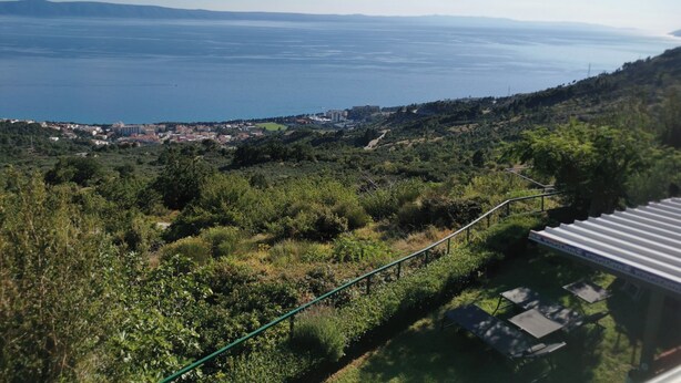 A coastal landscape with a view of the sea, a town in the distance, and a hillside with vegetation. - Apartment Ivo (Tucepi)