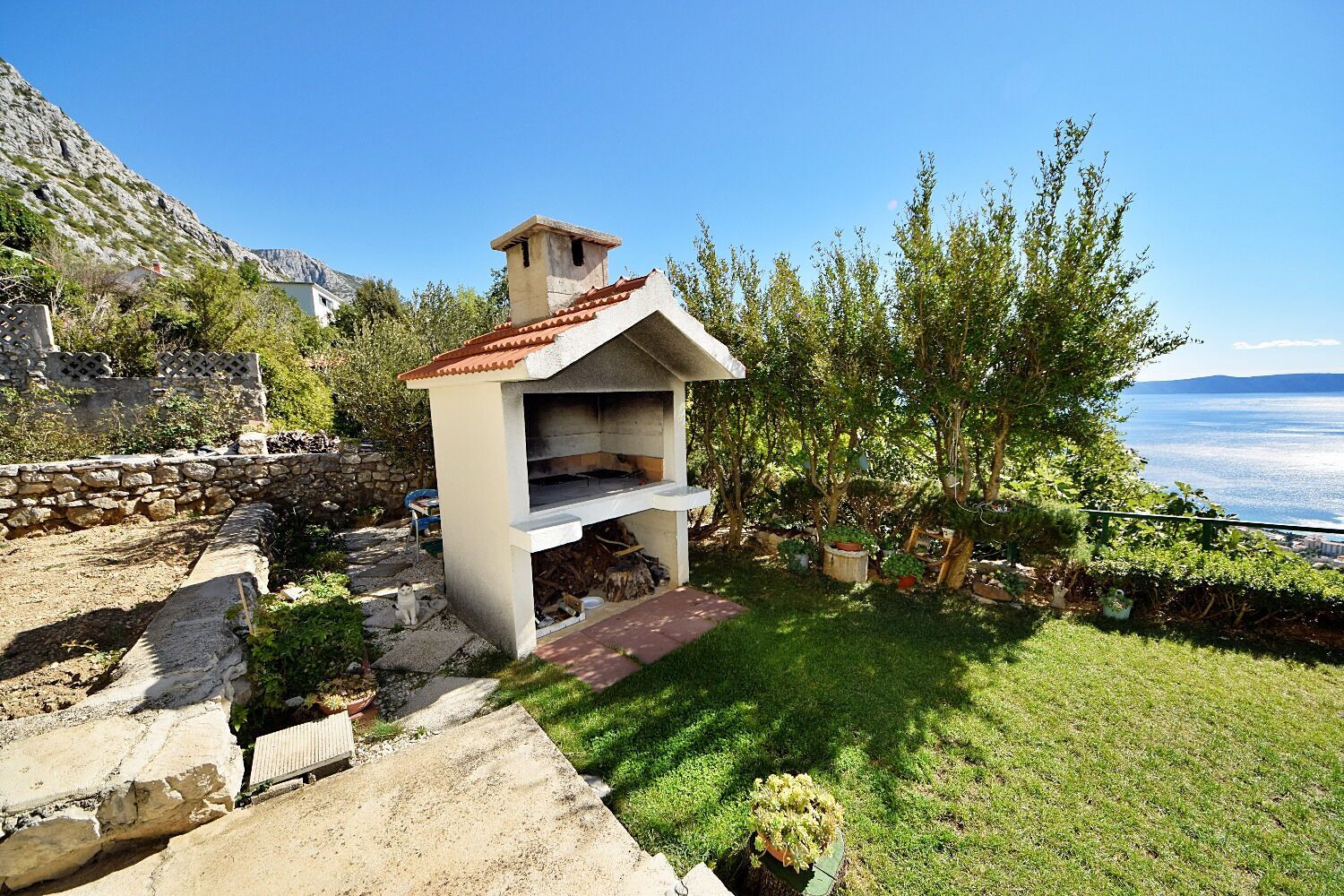 A stone structure with a chimney, a small porch, and a view of the sea.