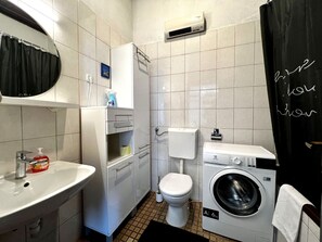 Une petite salle de bain comprenant un lavabo, des toilettes et un lave-linge.